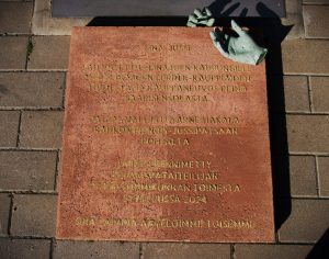 name plaque under a sculpture. two sculpture hands on top of the plaque