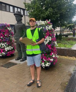 man standing with a yellow west on near a statue of a man